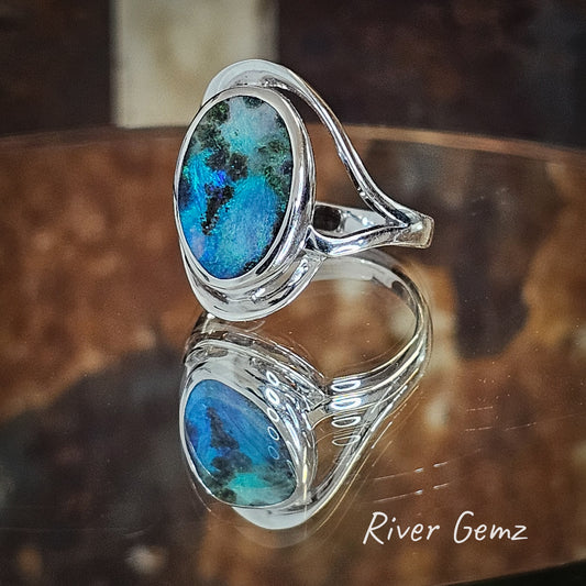 Blue, green and pink boulder opal besel set in sterling silver ring photographed on mirrored surface.