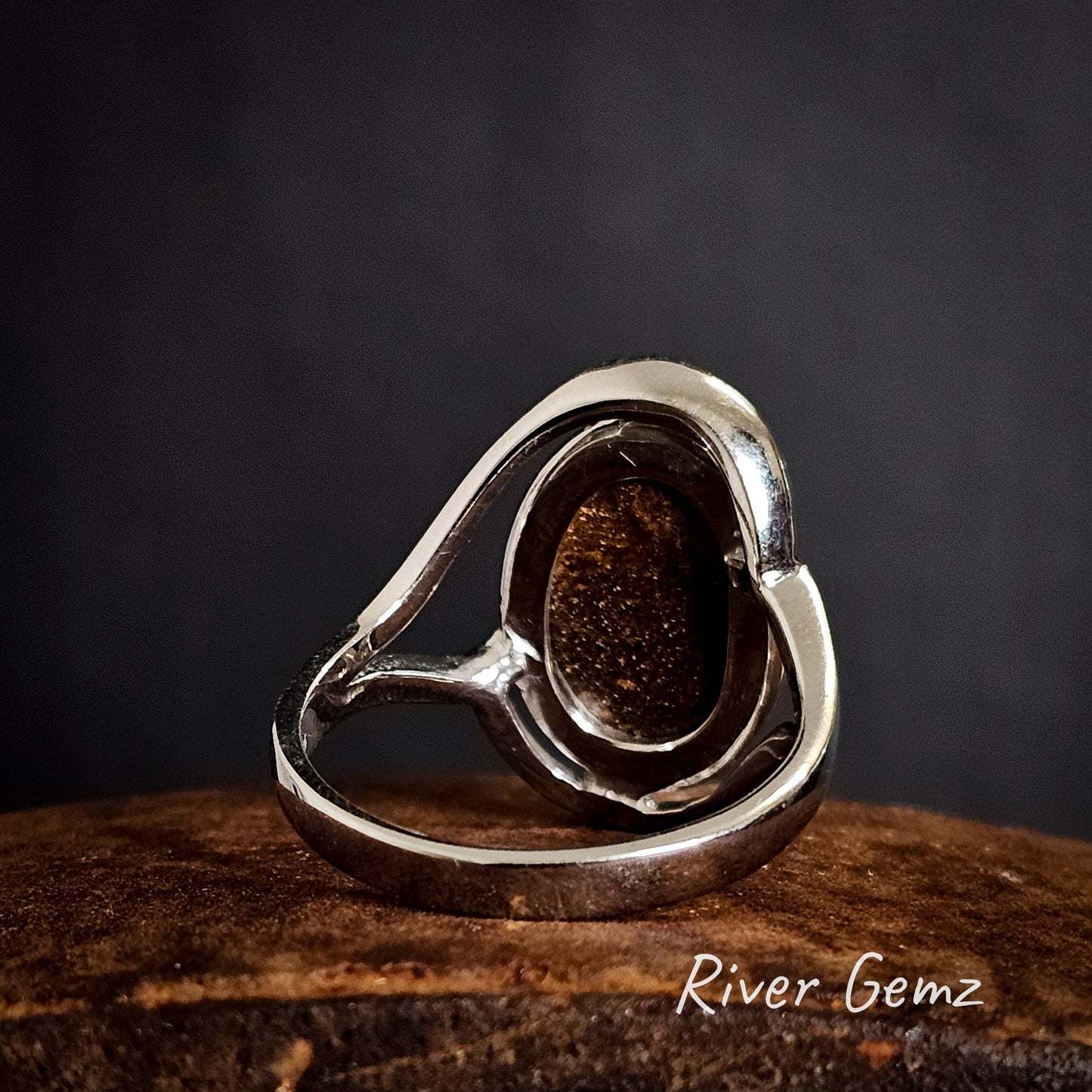 Back of the silver ring with the brown ironstone body of the boulder opal showing on a dark background, branded 'River Gemz'.