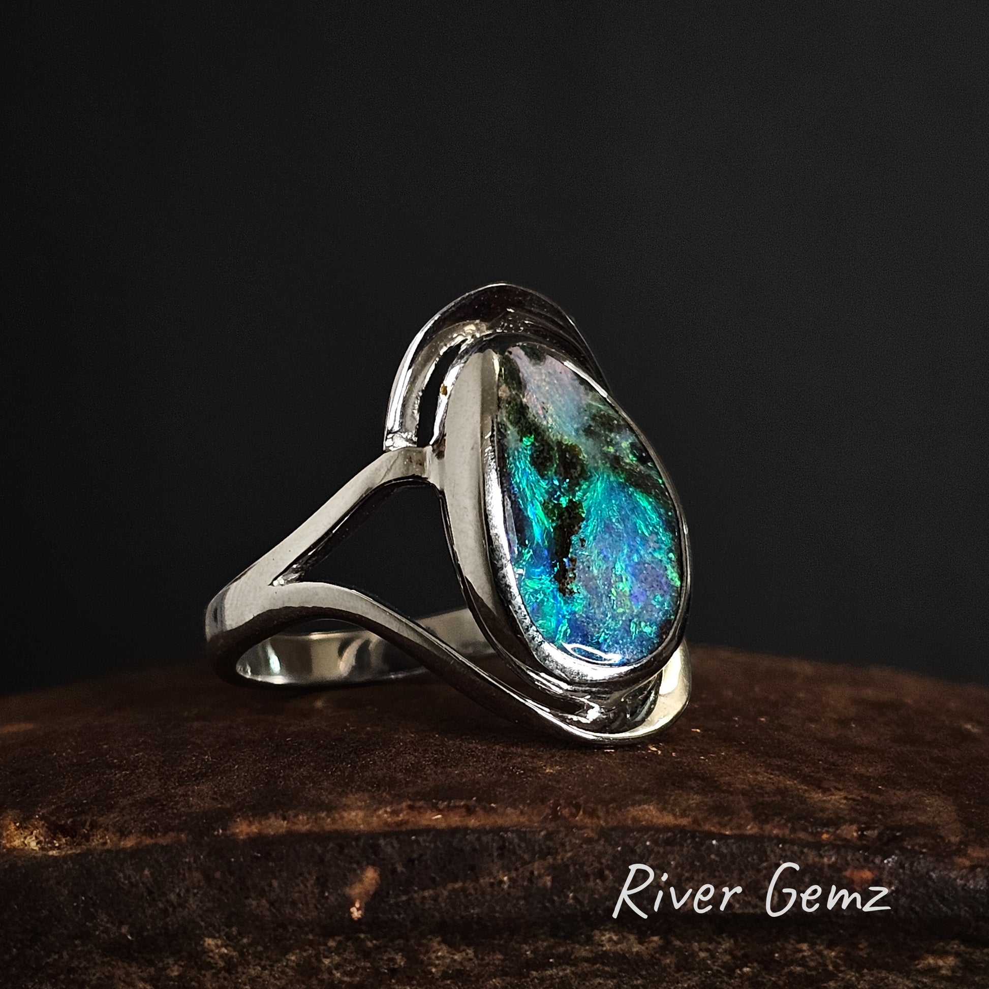 Sterling silver ring with a colourful boulder opal on a dark background, branded 'River Gemz'.
