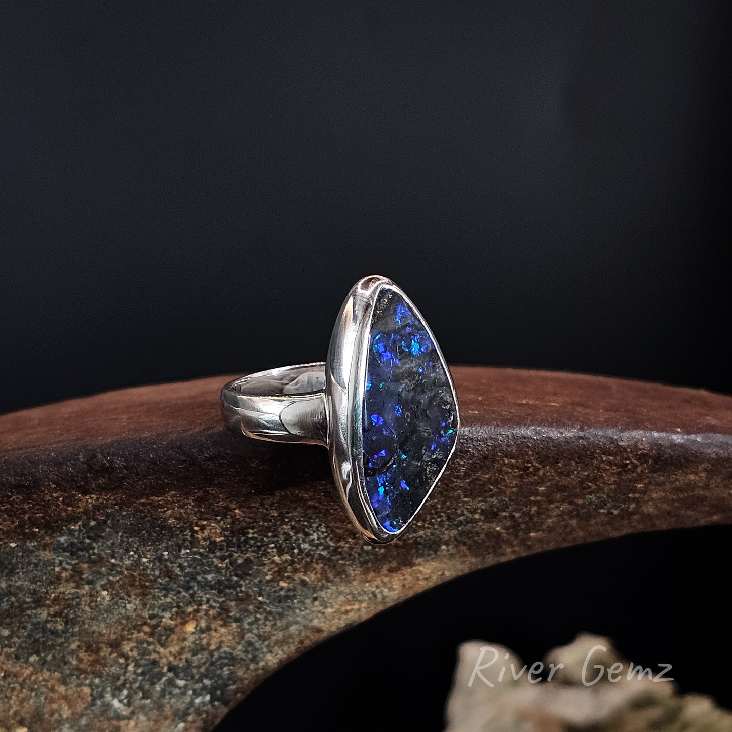 Large opal with blue, purple and a hint of green besel set in wide band sterling silver ring.