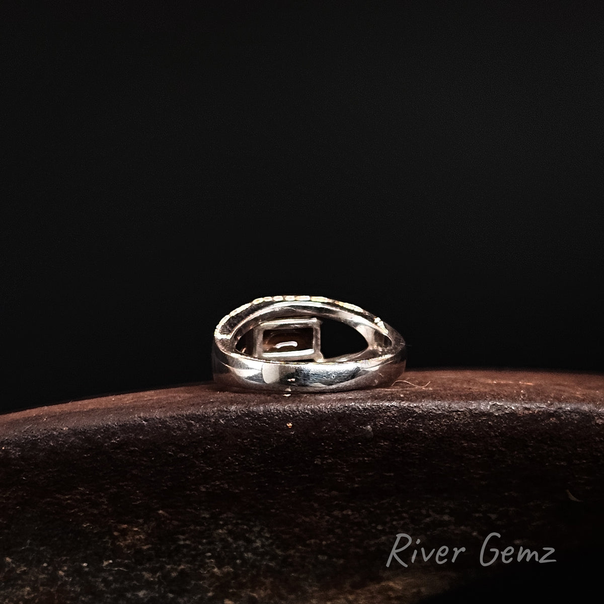 Rear view of silver ring showing the ironstone matrix of the boulder opal, displayed on a dark wooden surface against a black background. The brand name 'River Gemz' is visible in the bottom right corner.