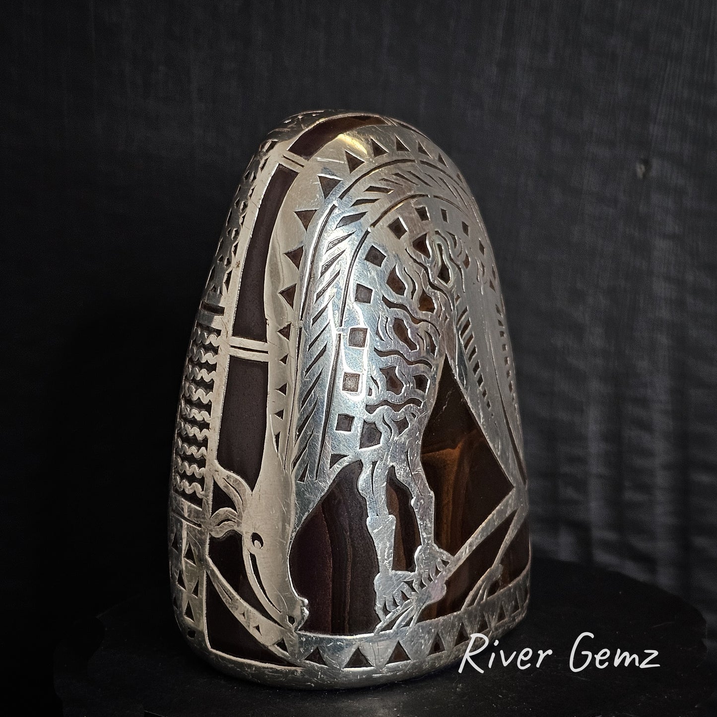 Decorative silver ornament with intricate design of a kangaroo surrounding the boulder opal specimen on a dark background, featuring the brand 'River Gemz'.