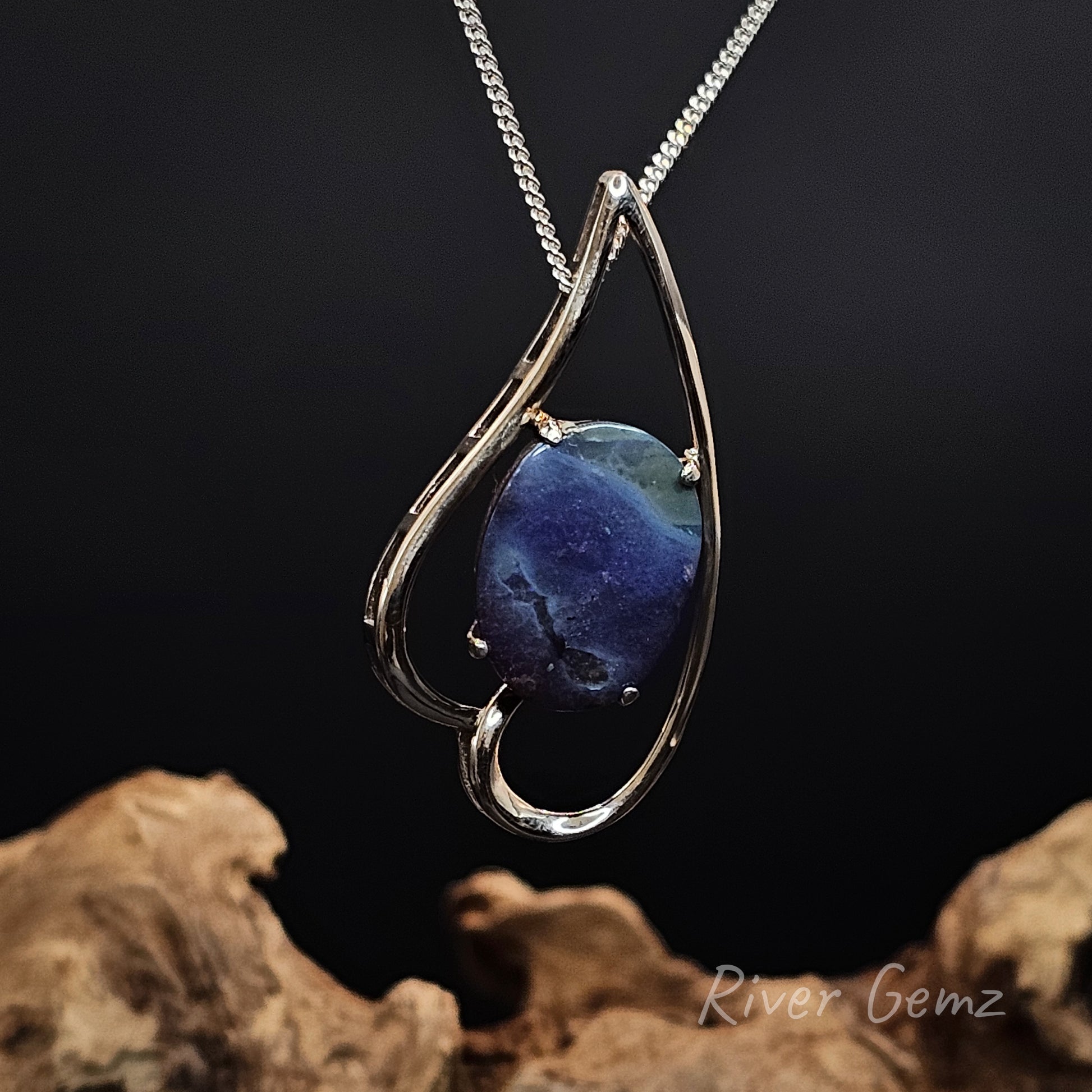 Silver pendant with a blue stone on a dark background