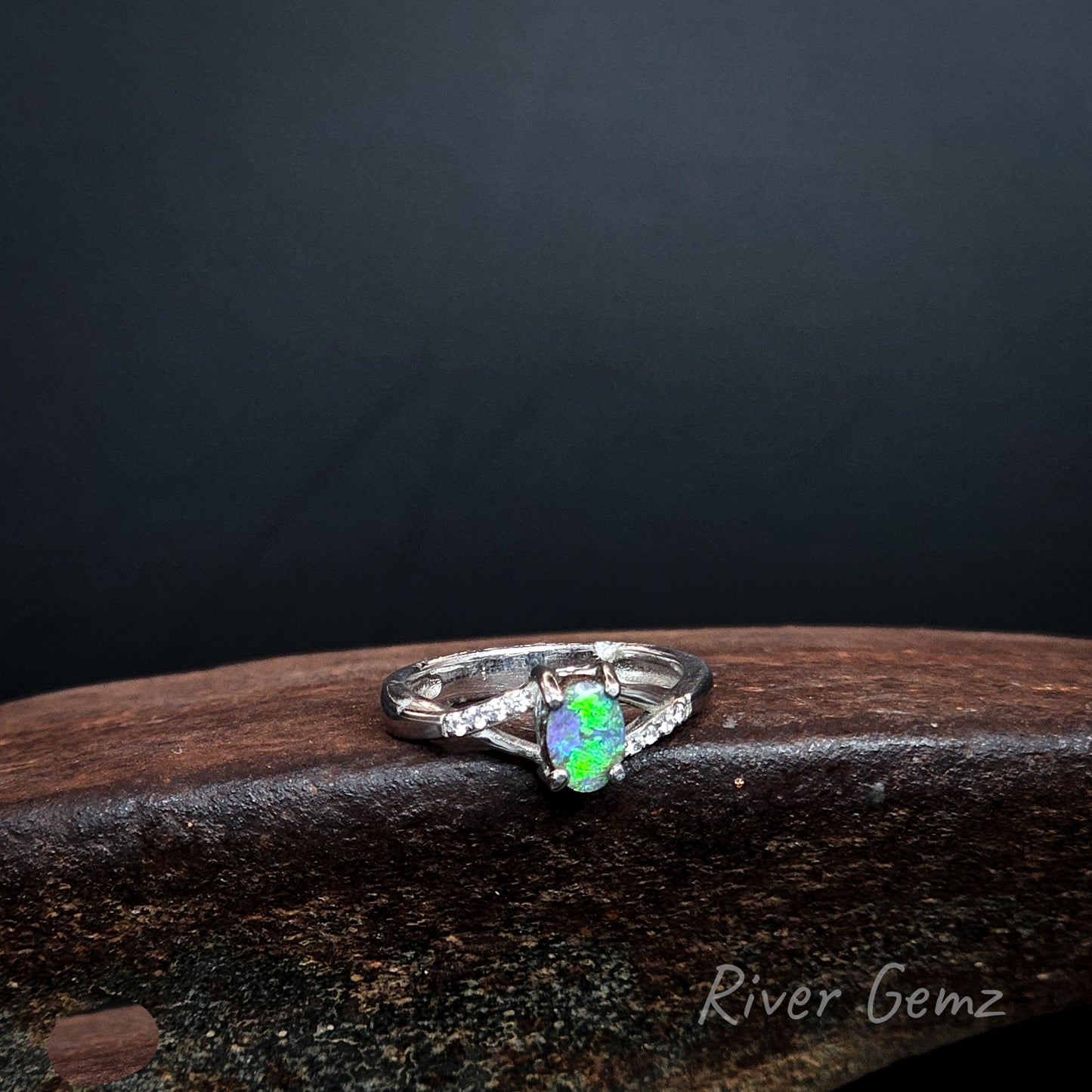 Bright green opal claw set in sterling silver ring with channel set white topaz stones on the shoulders.