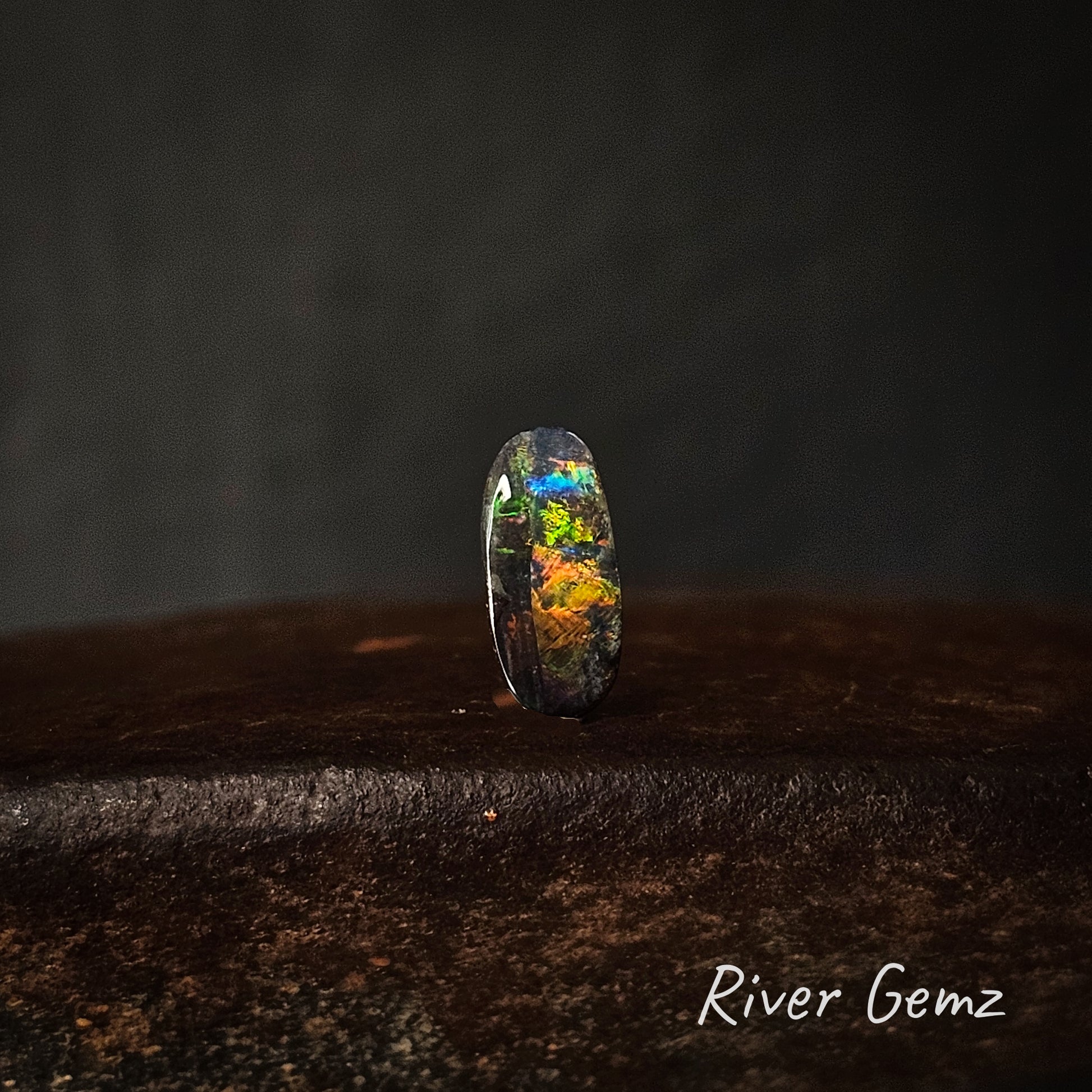 Opal stone on a dark surface with 'River Gemz' branding