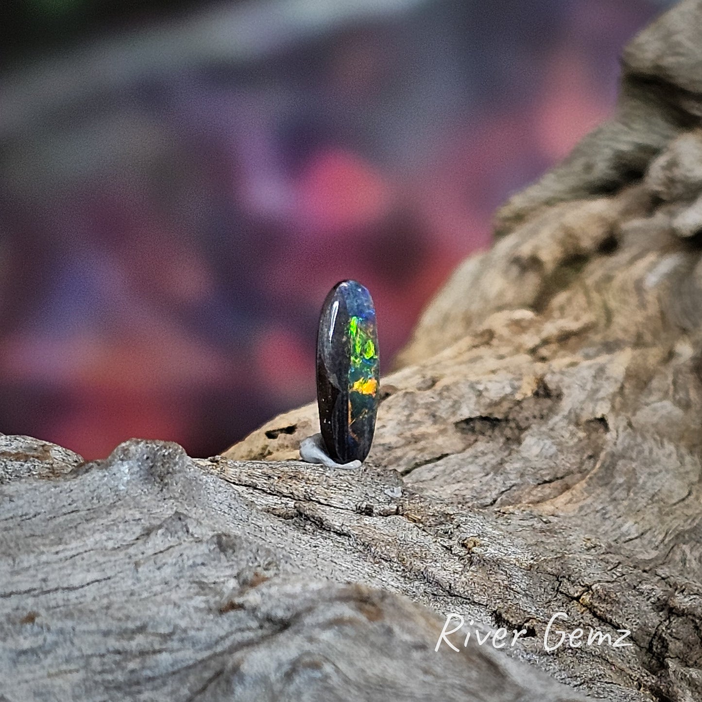 Side view of the unset boulder opal reveals bright green and orange and shows the solid opal thickness.