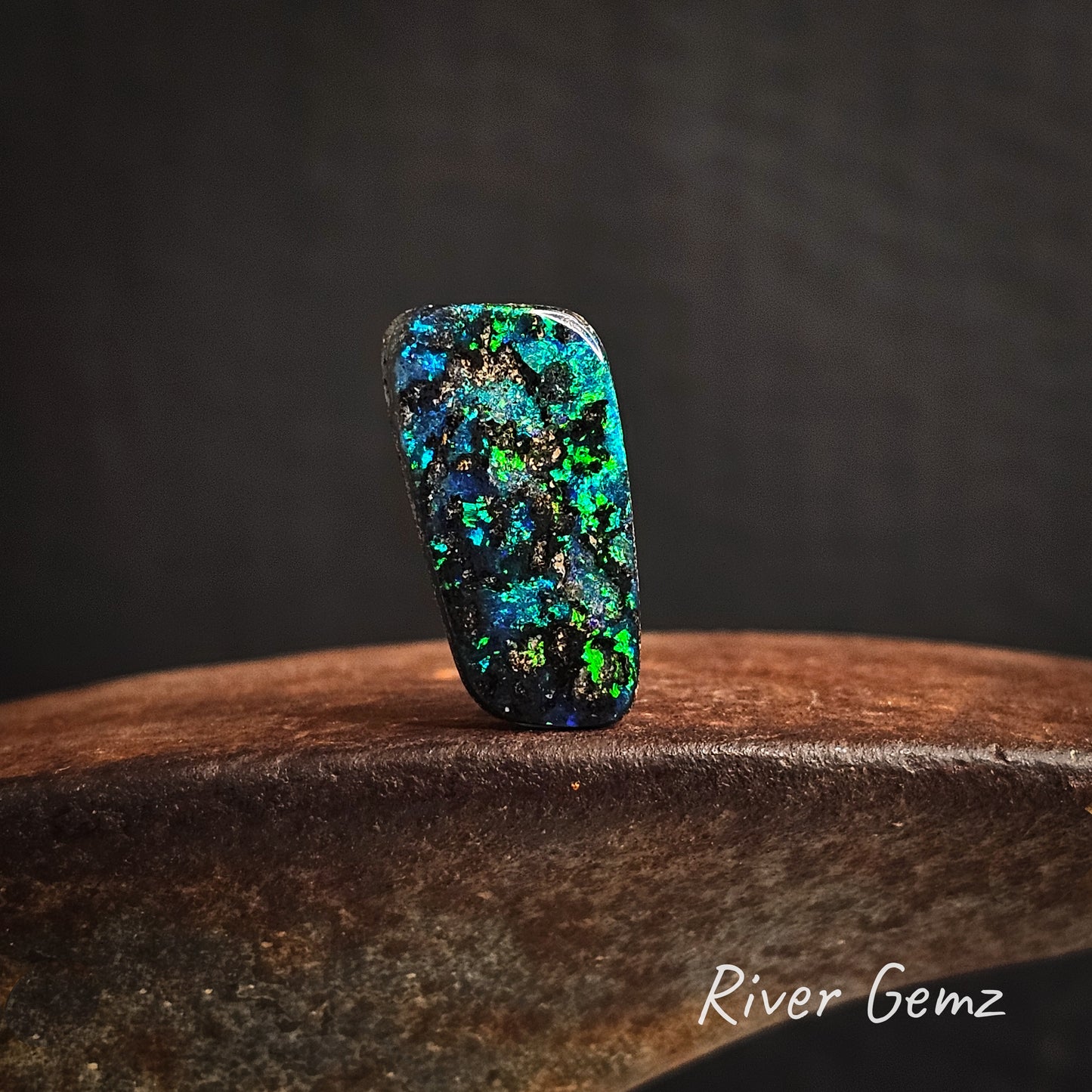 Multicolored opal stone on a cast iron surface with a dark background