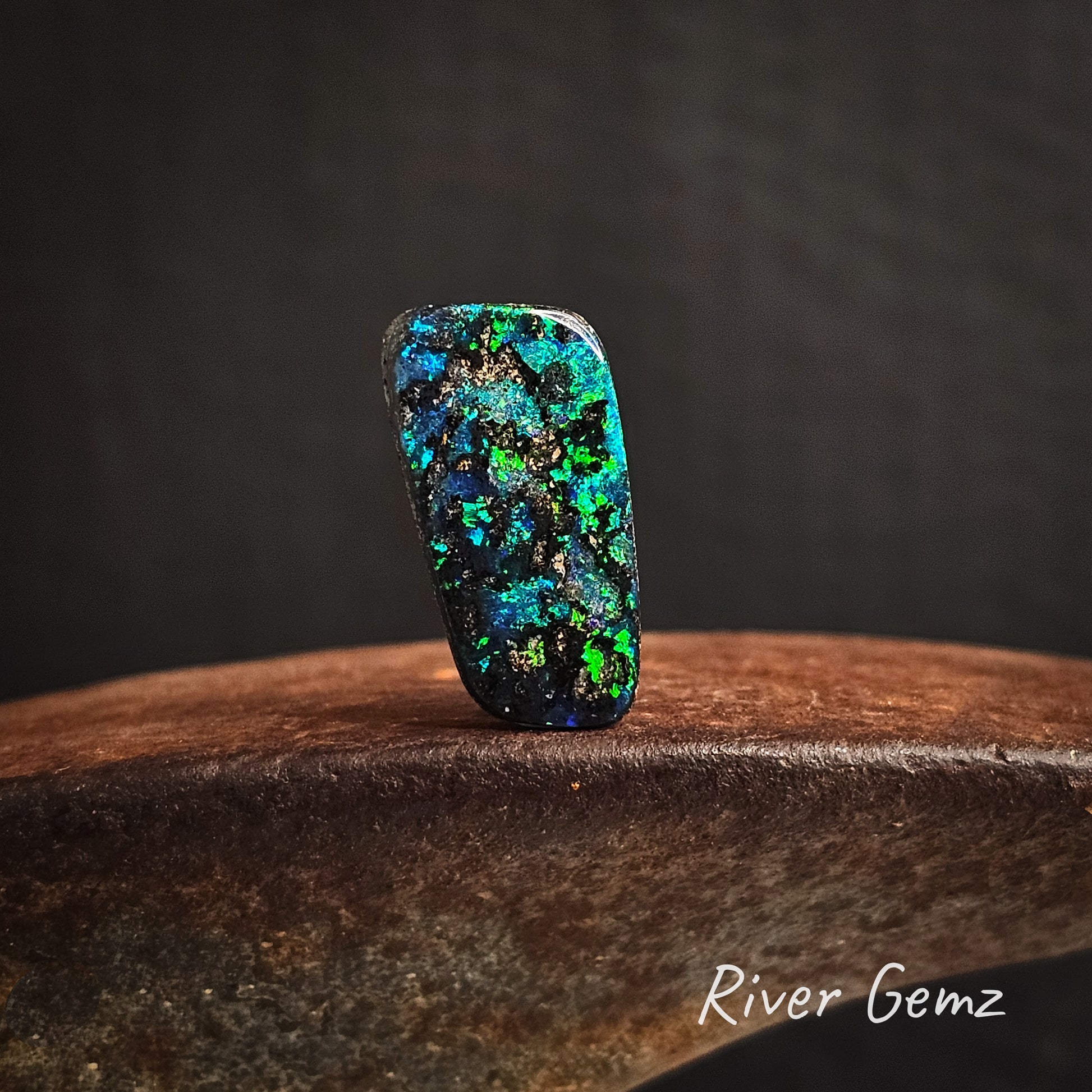 Multicolored opal stone on a cast iron surface with a dark background