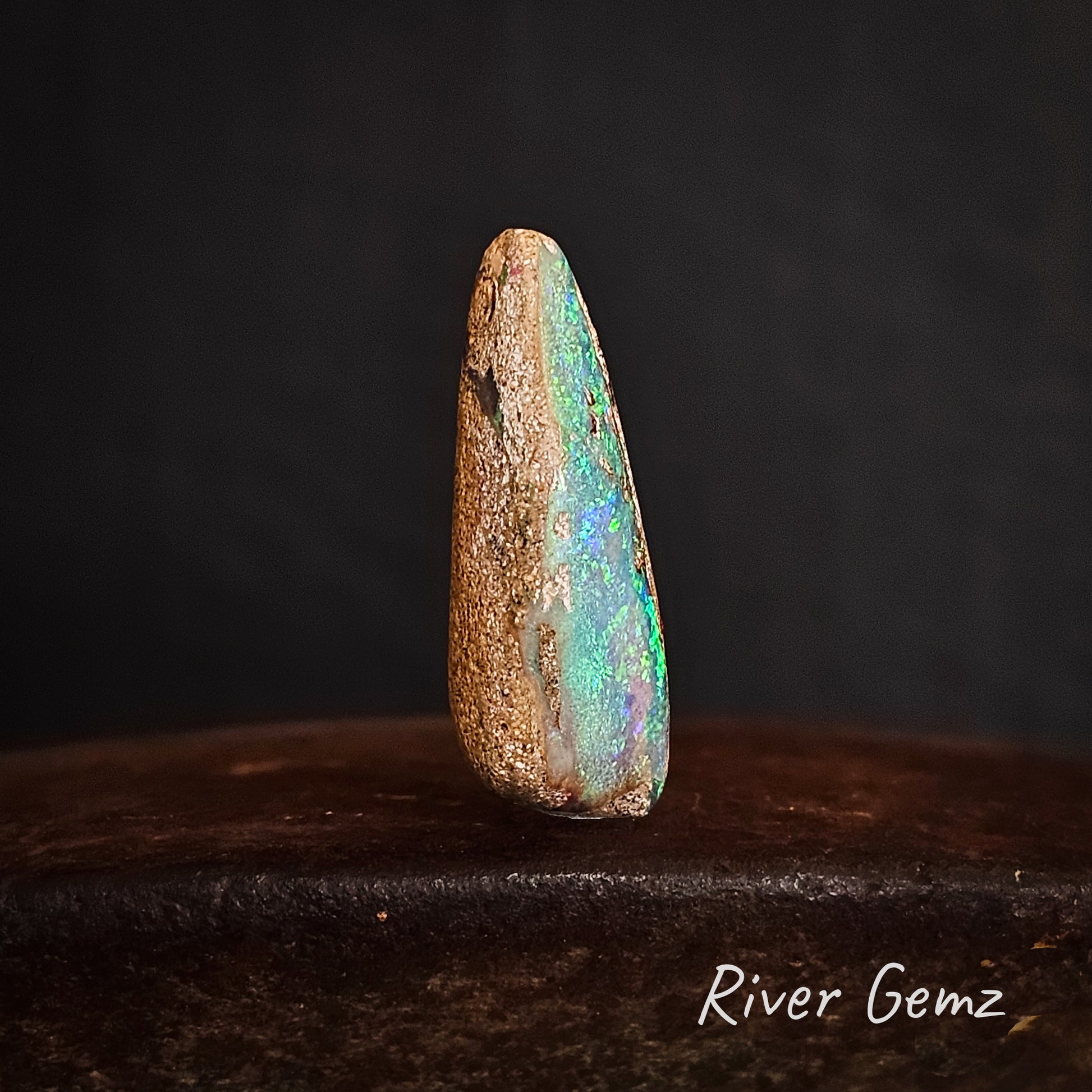 Side view of unset pipe opal showing the light brown base tone of the boulder opal.