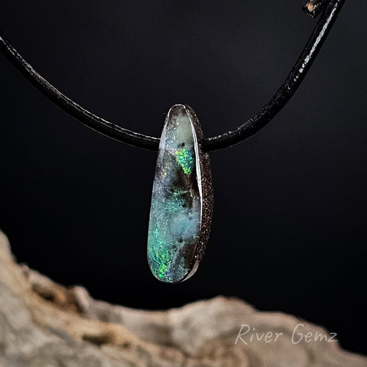 Opal pendant on a black cord with a dark background