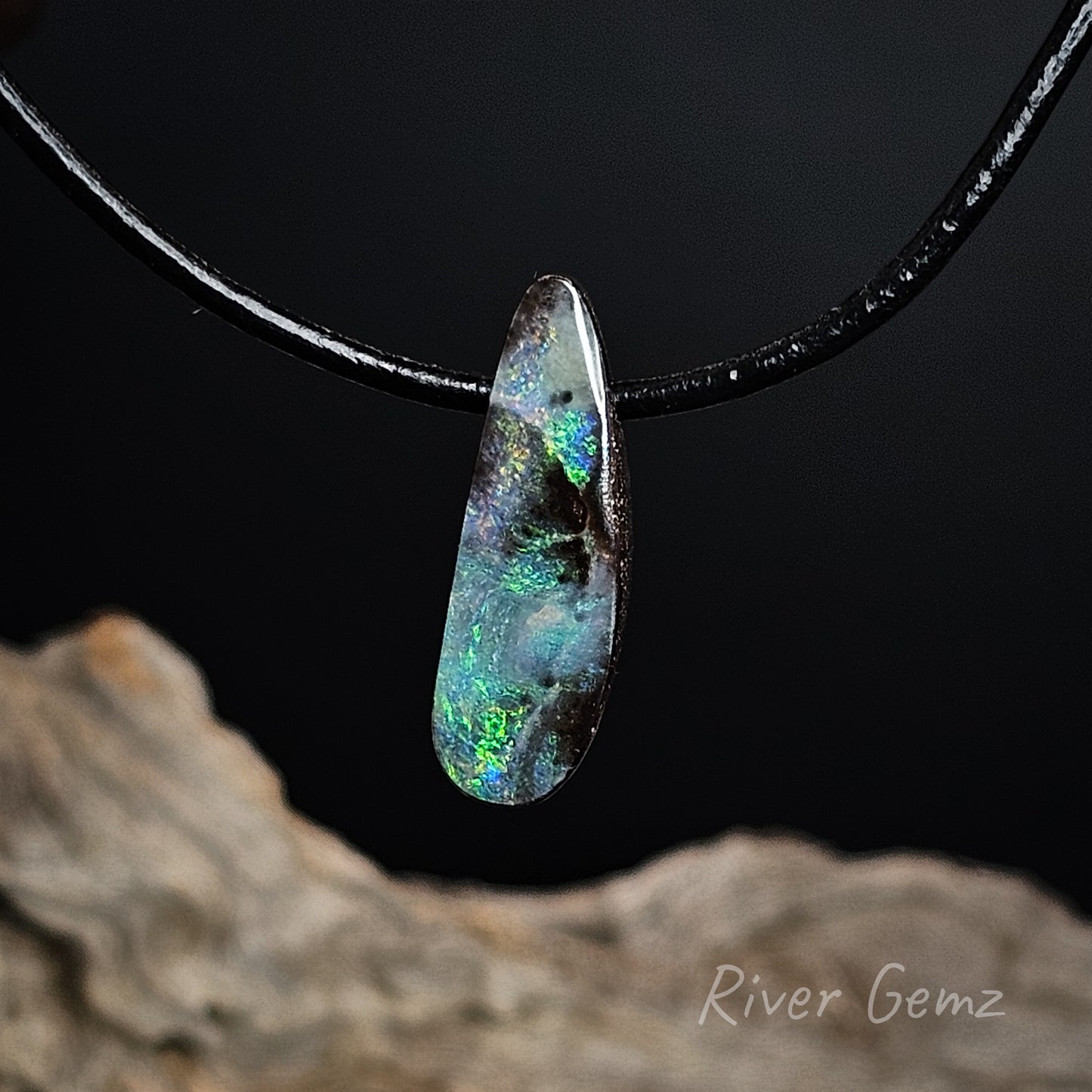 Opal pendant on a black cord with a dark background