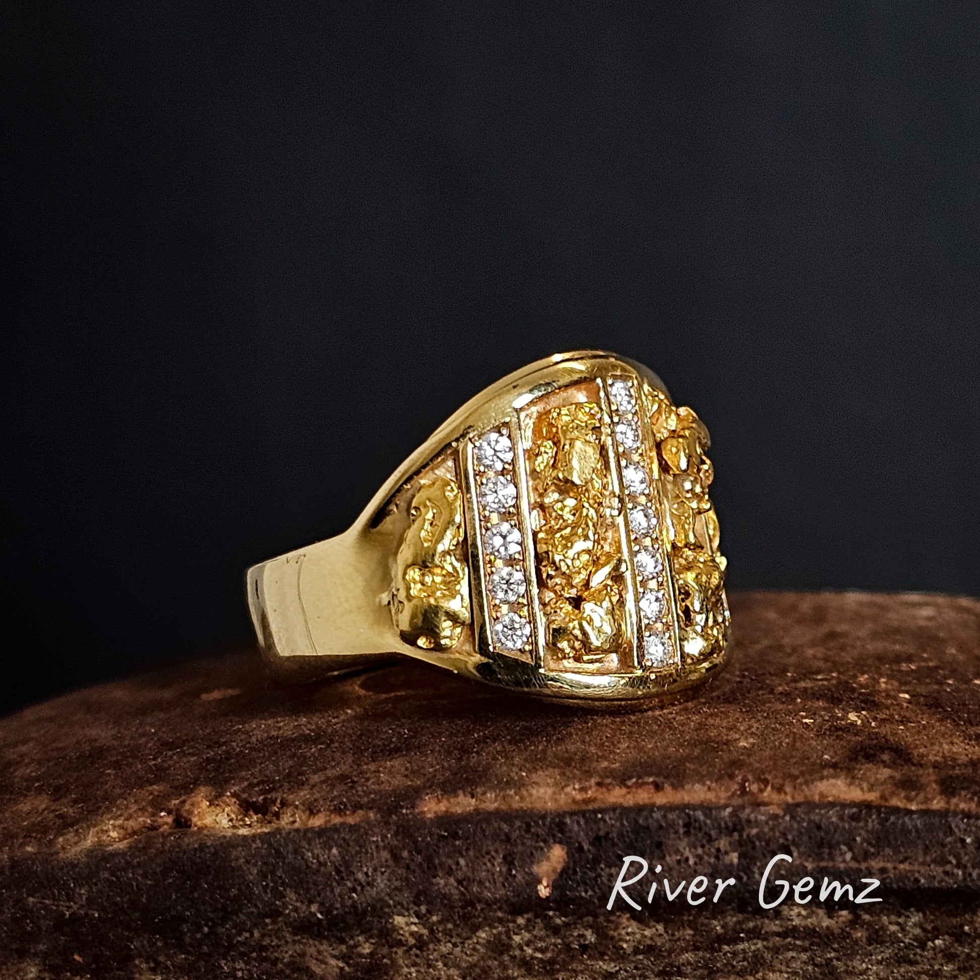 Gold ring with alternating vertical bands of gold nuggets and diamonds on a dark background, featuring the brand 'River Gemz'.
