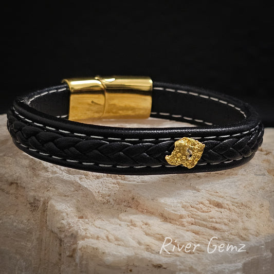 Gold nugget on a black leather bracelet together with a gold coloured locking mechanism.