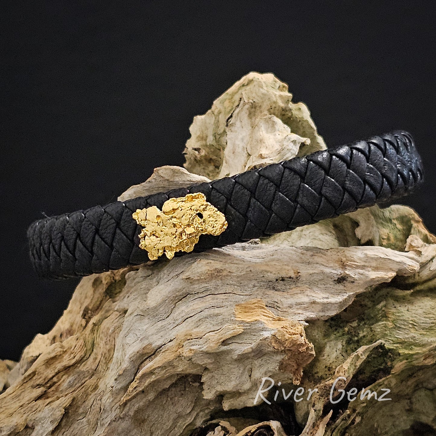 Large yellow gold nugget centred on a black leather bracelet.