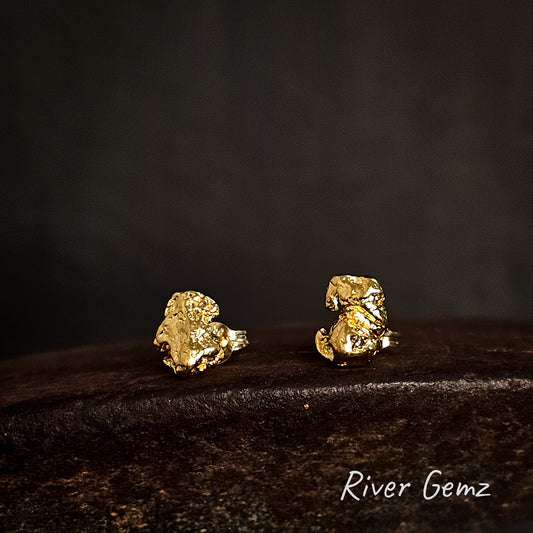 Gold nugget earrings on a dark surface with 'River Gemz' branding.