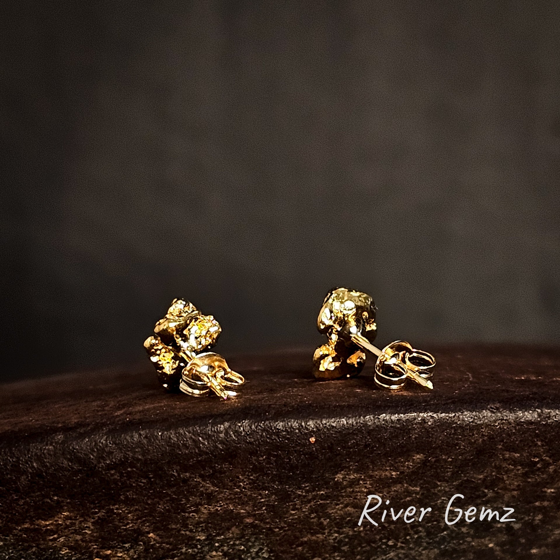 Back view of gold nugget earrings showing the long posts and butterflies on a dark surface with 'River Gemz' branding.