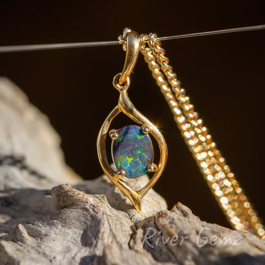 Four very similar photos of the yellow gold pendant. Cabochon cut opal secured with 4 claws to the leaf shaped pendant. Good sized bail passes through the eyelet at the top of the pendant design. Gold chain hangs freely from the wire that supports the pendant.