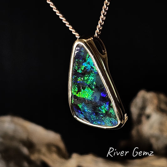 Opal pendant necklace with a gold chain on a dark background, featuring the brand 'River Gemz'.