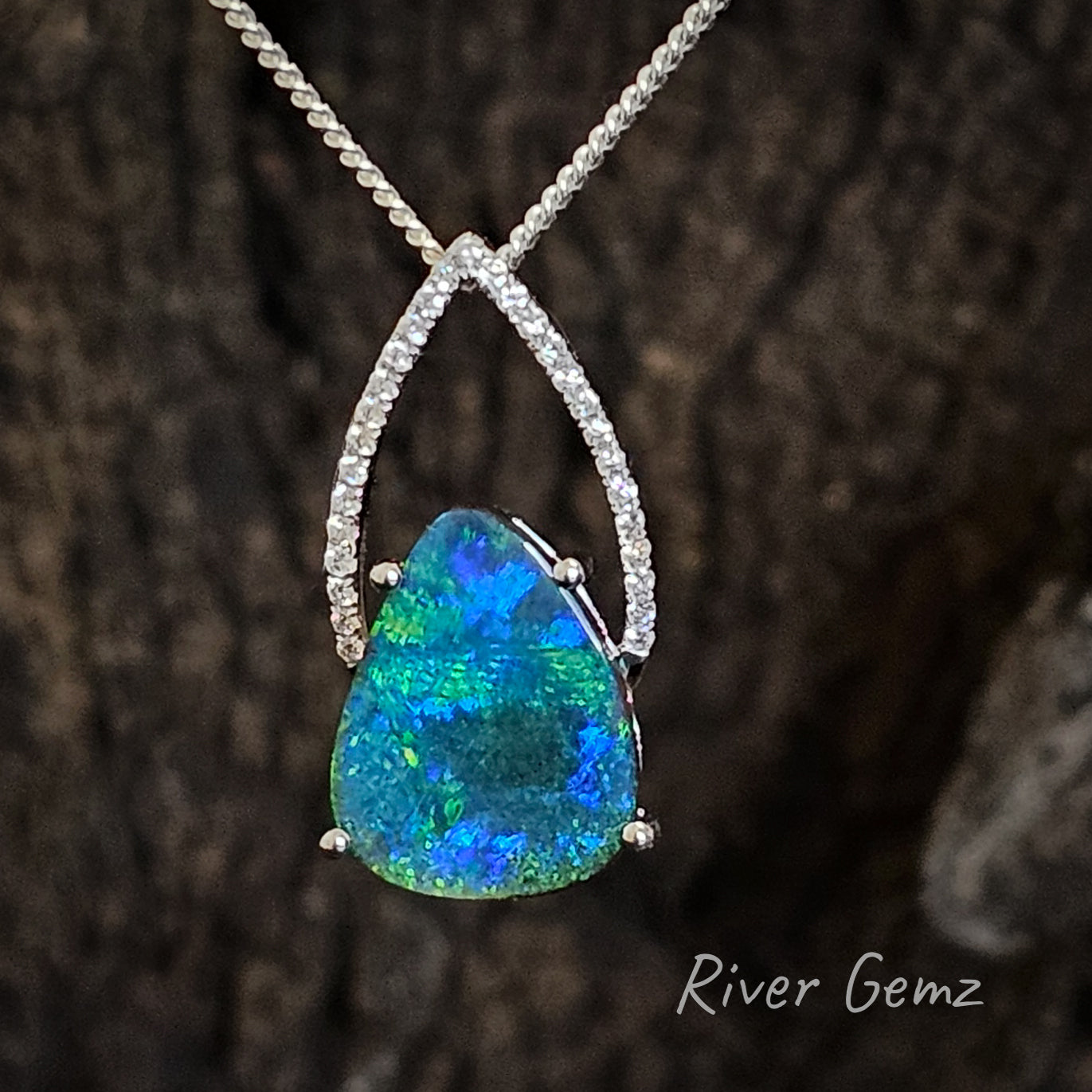 A diamond, white gold and boulder opal necklace photographed with a rough timber background.