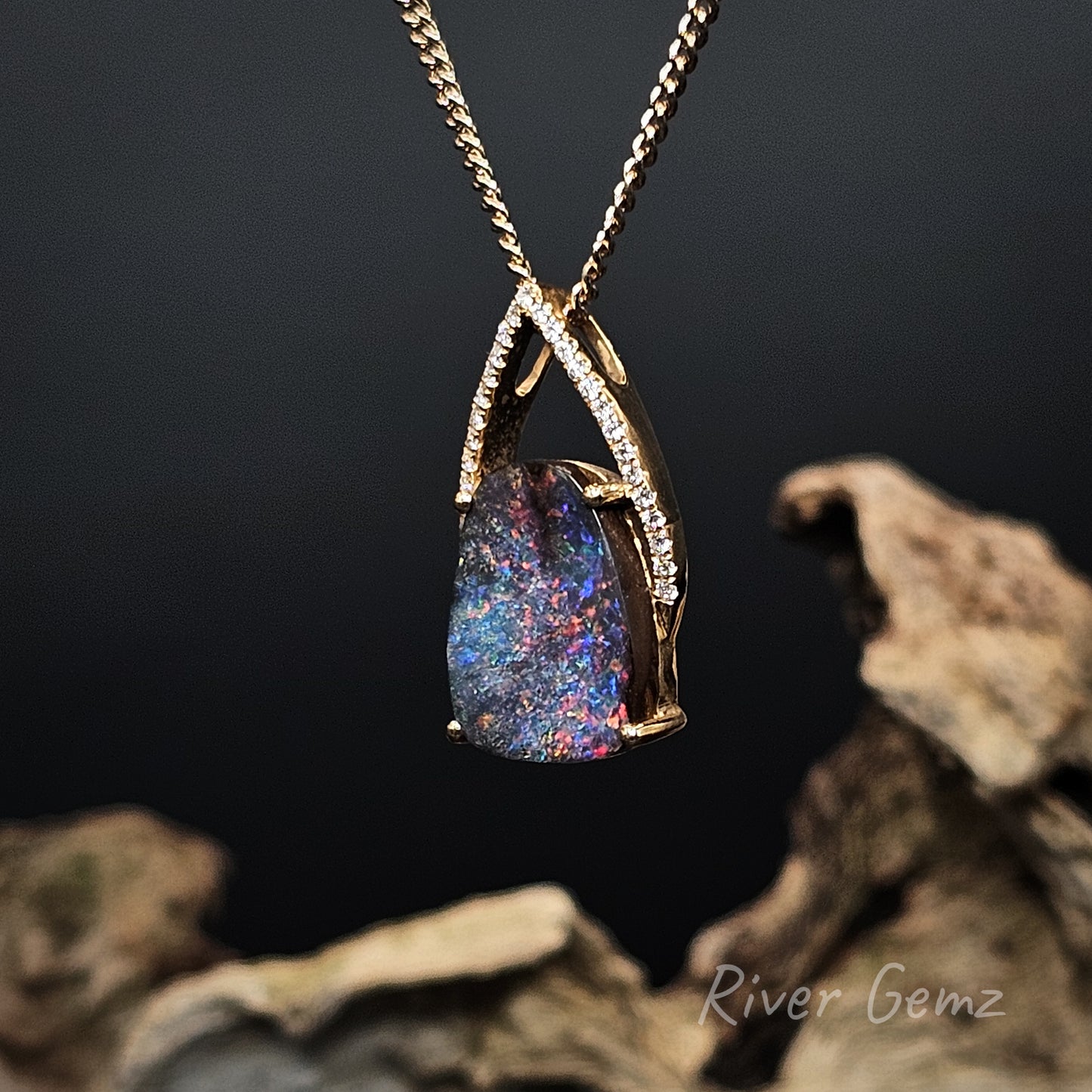 Necklace with a colorful boulder opal and channel set diamonds on a dark background
