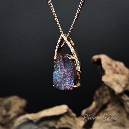 Necklace with a colorful boulder opal and channel set diamonds on a dark background