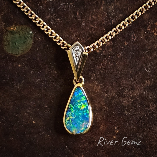 Tear drop shaped boulder opal pendant with an art nouveau style of bail with diamond all in 18K yellow gold.