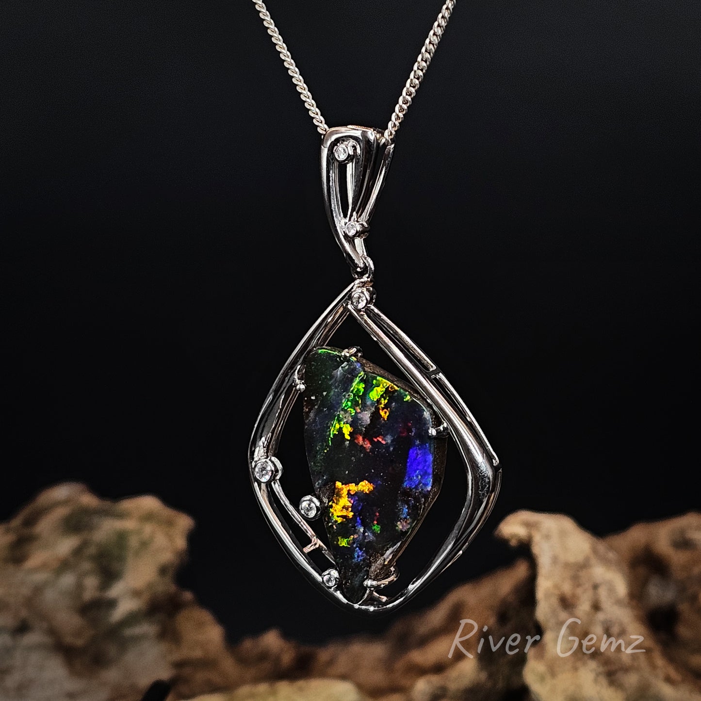 Opal and white diamonds pendant in white gold setting on a dark background with 'River Gemz' branding.