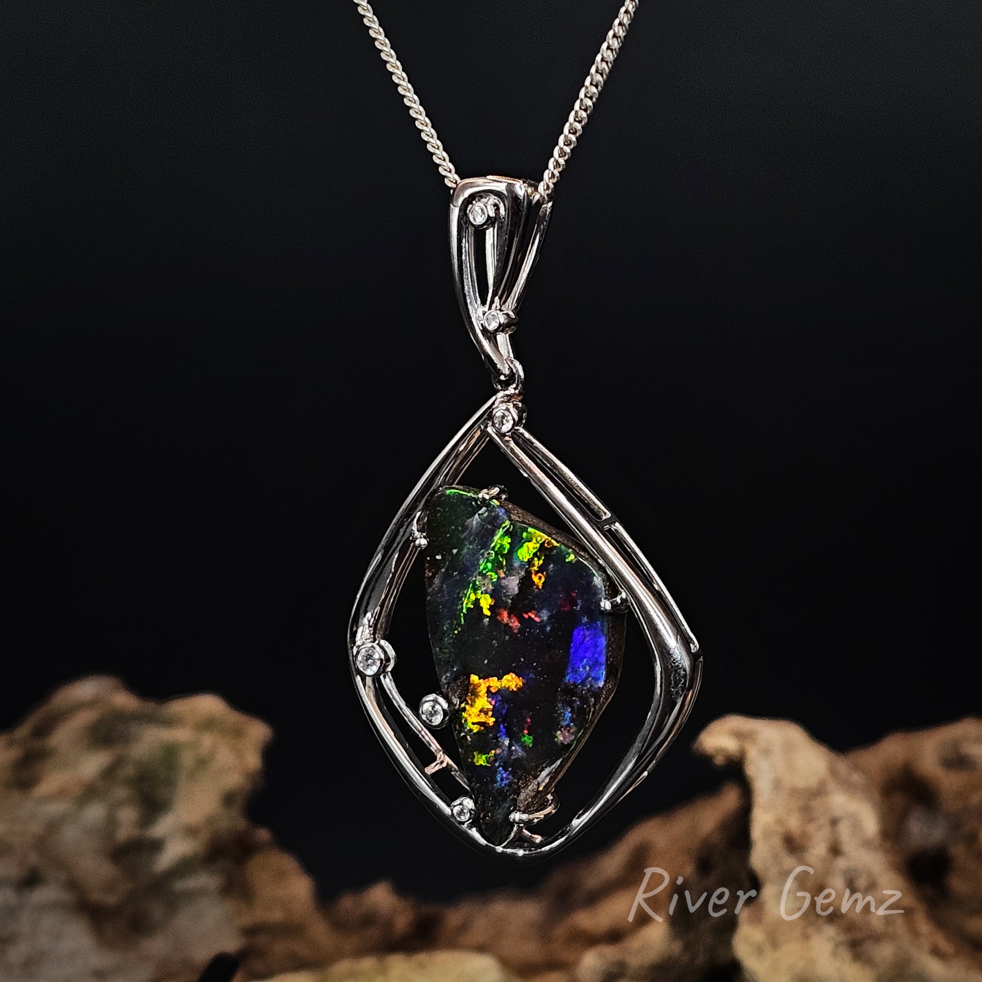Opal and white diamonds pendant in white gold setting on a dark background with 'River Gemz' branding.