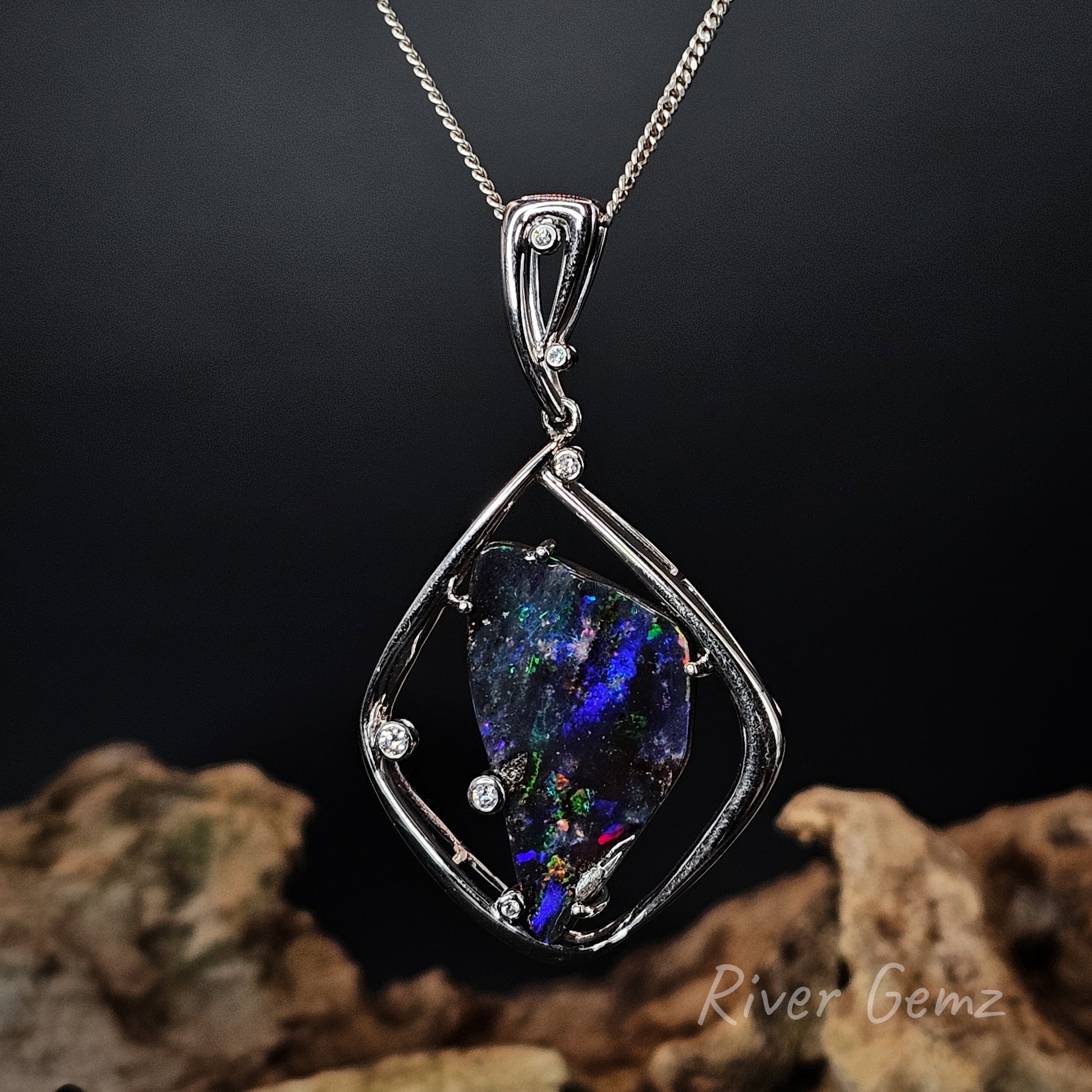 High grade white gold pendant with a colorful boulder opal on a dark background