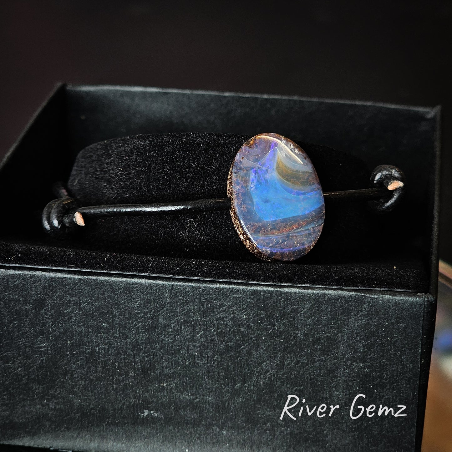 Ironstone host of the boulder opal visible through the boulder crystal opal on a leather wristband.