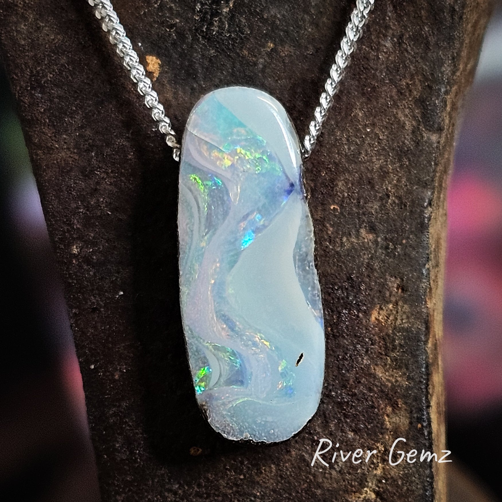 Long oval shaped opal with swirls of colour on a silver chain.