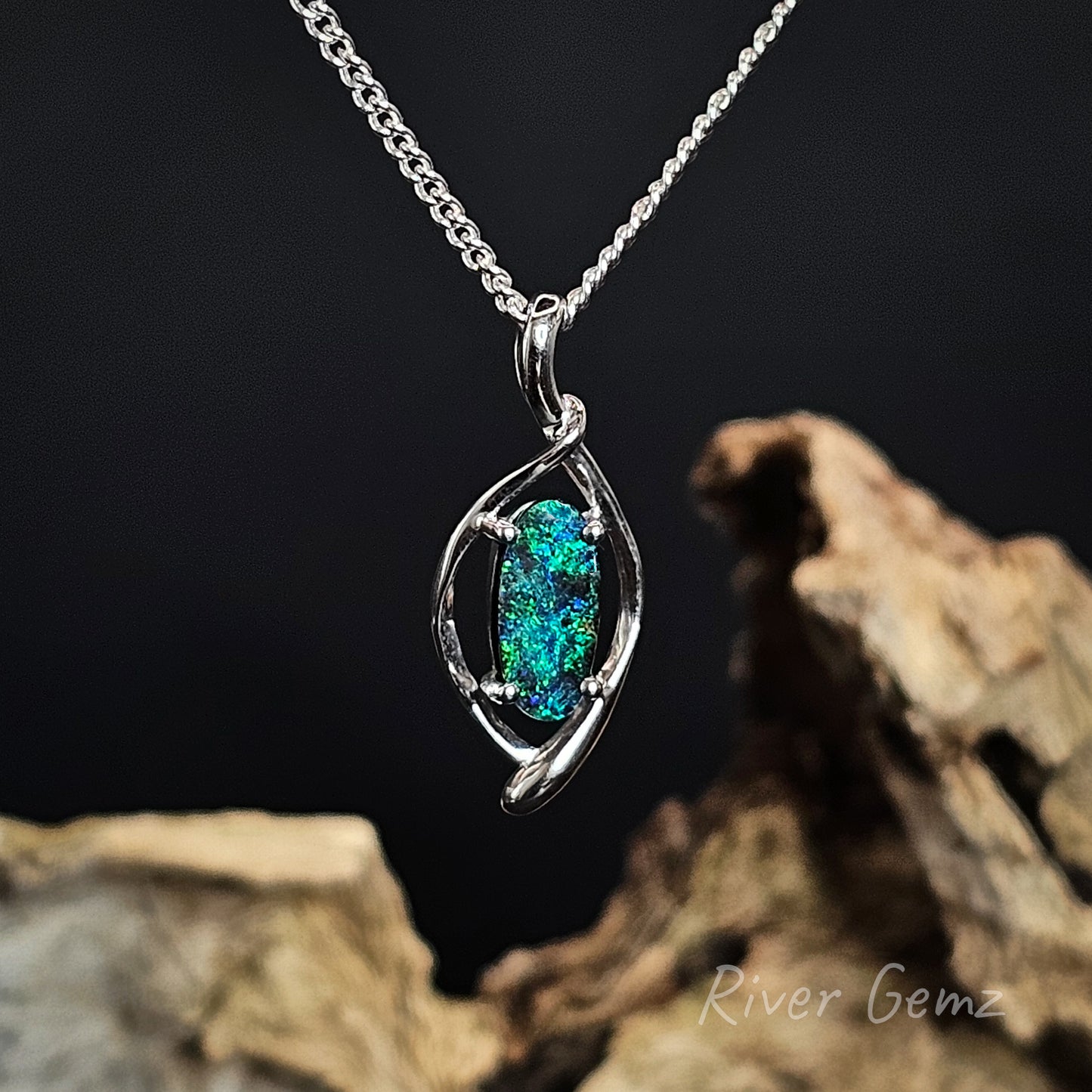 Silver necklace with a oval shaped boulder opal on a dark background