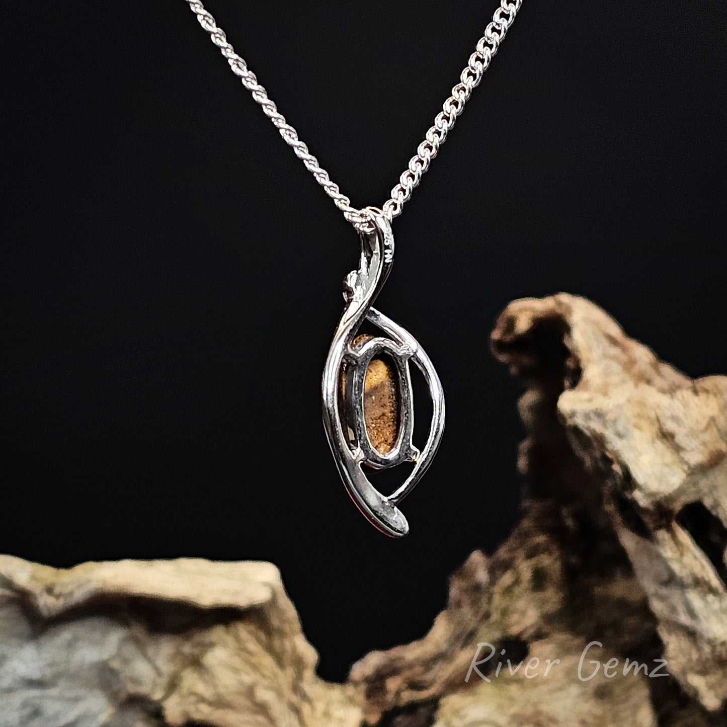 Rear view of silver pendant showing the ironstone matrix of the boulder opal on a dark background