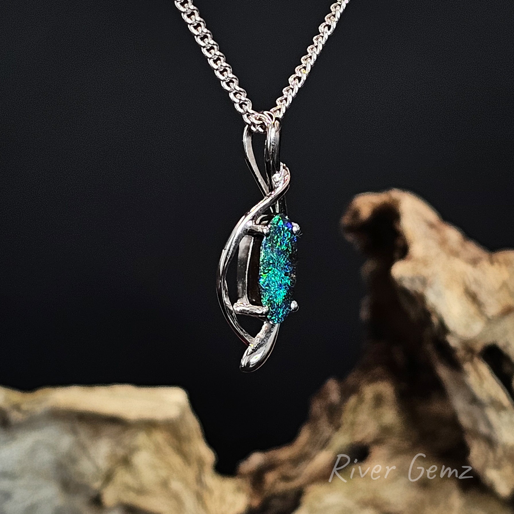 Silver pendant with a blue gemstone on a dark background