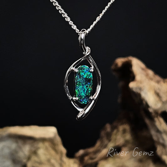 Silver pendant with a green gemstone on a dark background