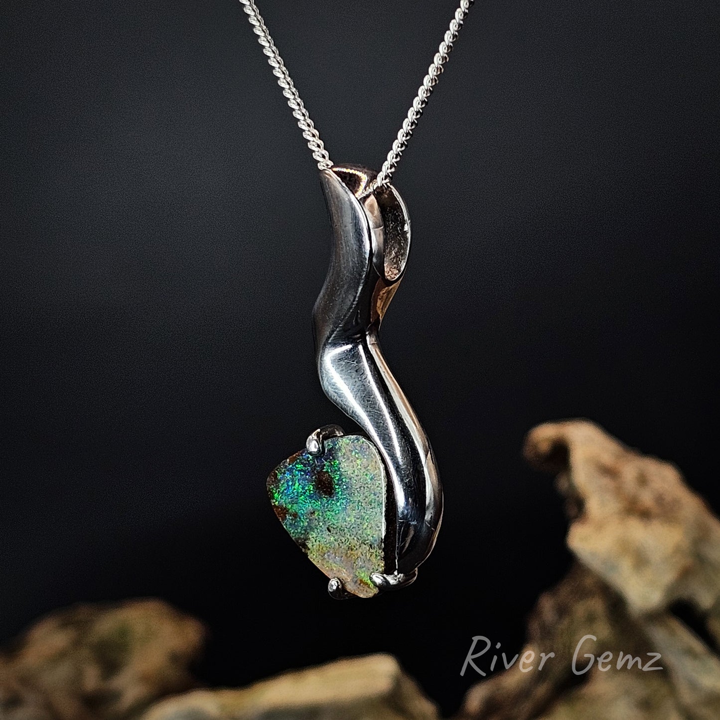 Silver pendant with a green gemstone on a dark background