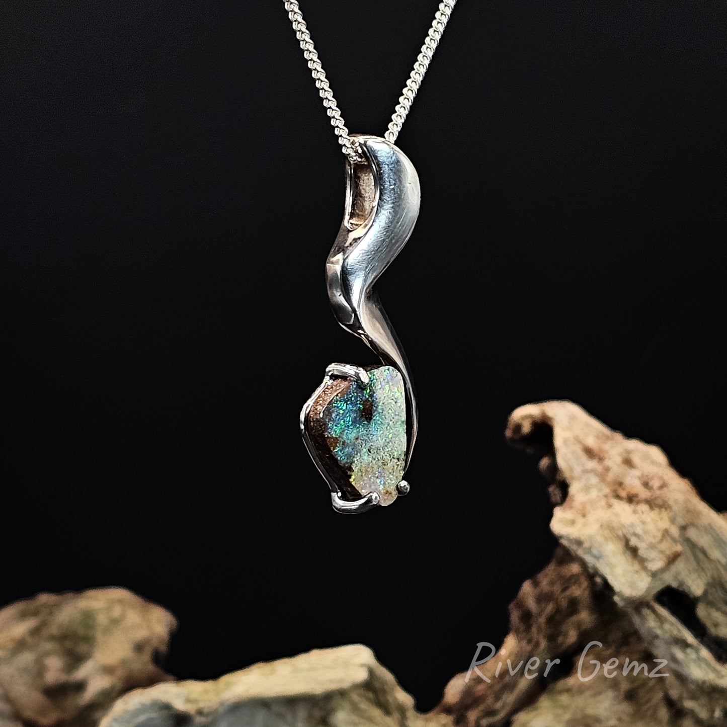 Silver pendant with a green stone on a dark background