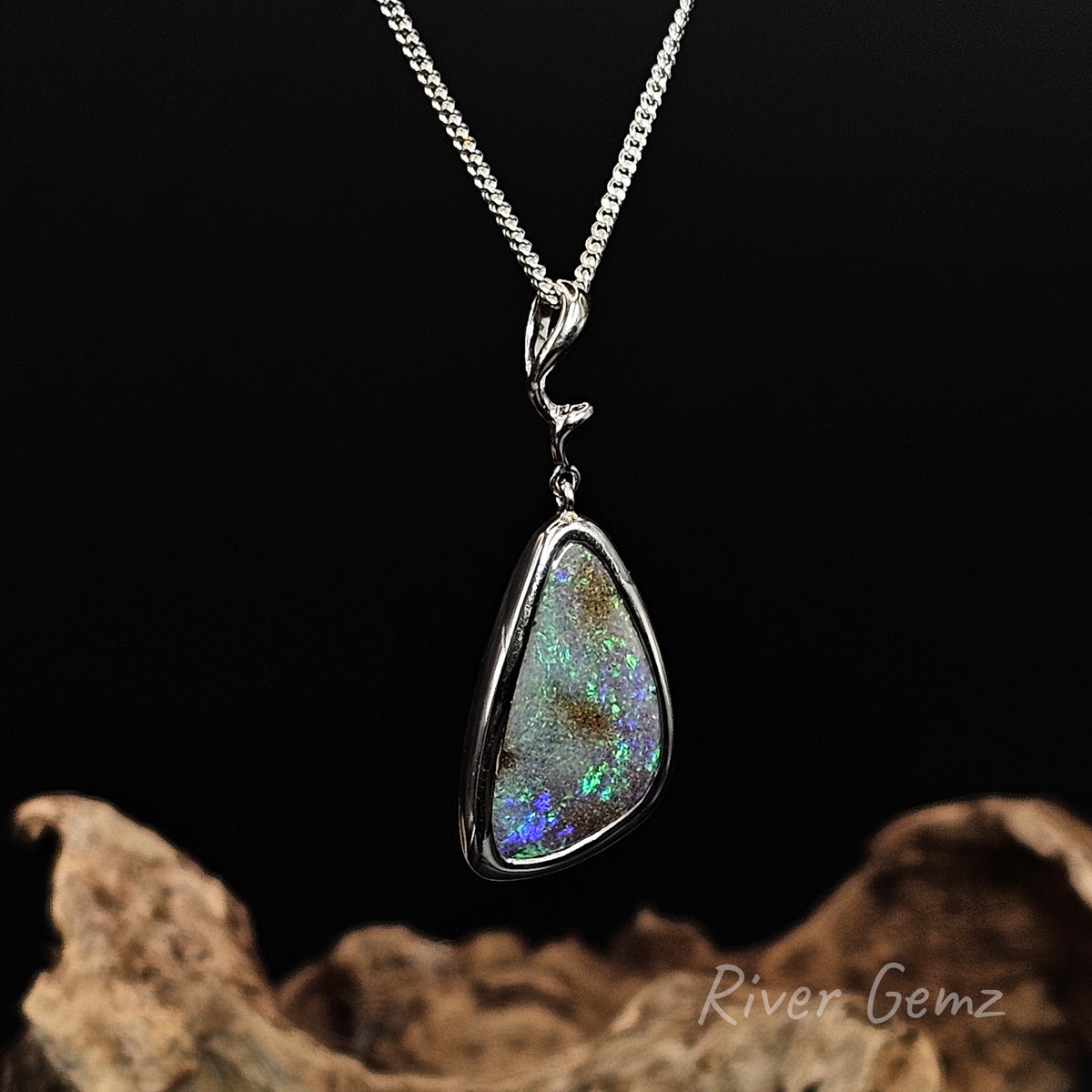 Blue and green boulder opal with a flash of purple in the bottom corner besel set in silver necklace.