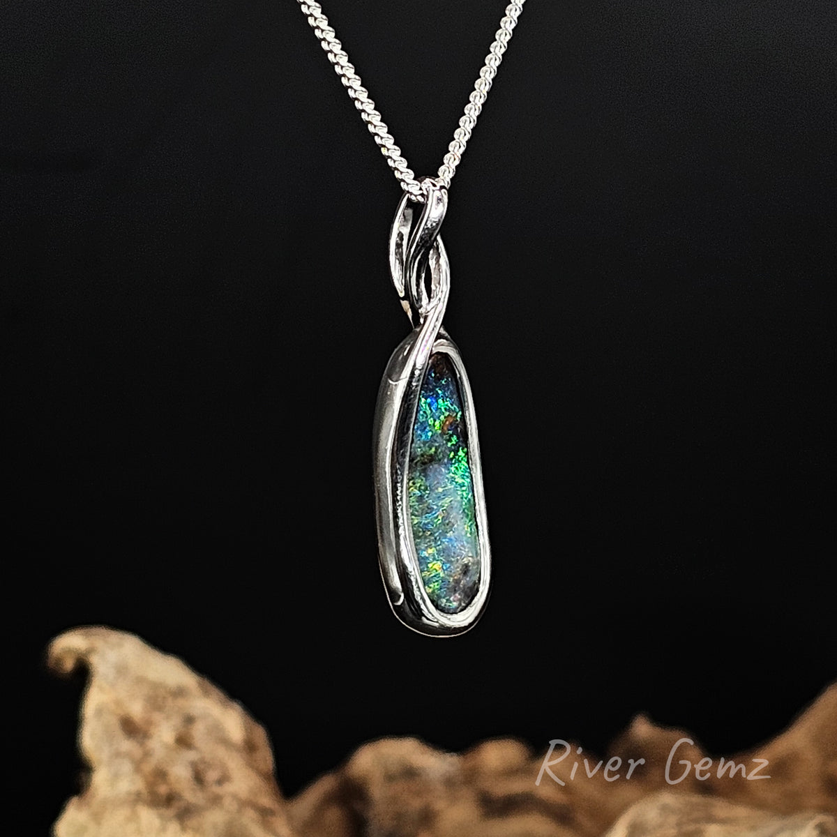 Slightly side on view of silver pendant showing the twist design above the opal where the silver chain passes through.