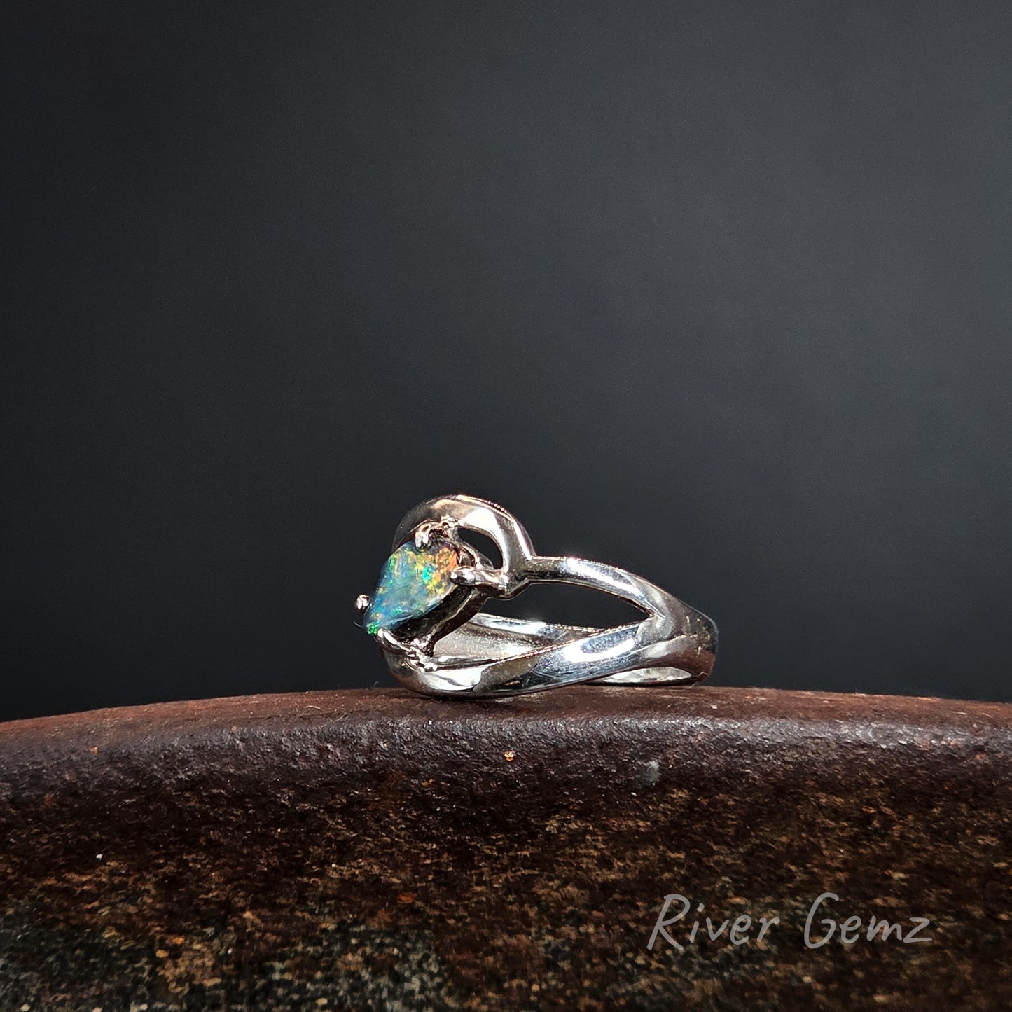 Silver ring with a claw set boulder opal on a dark background