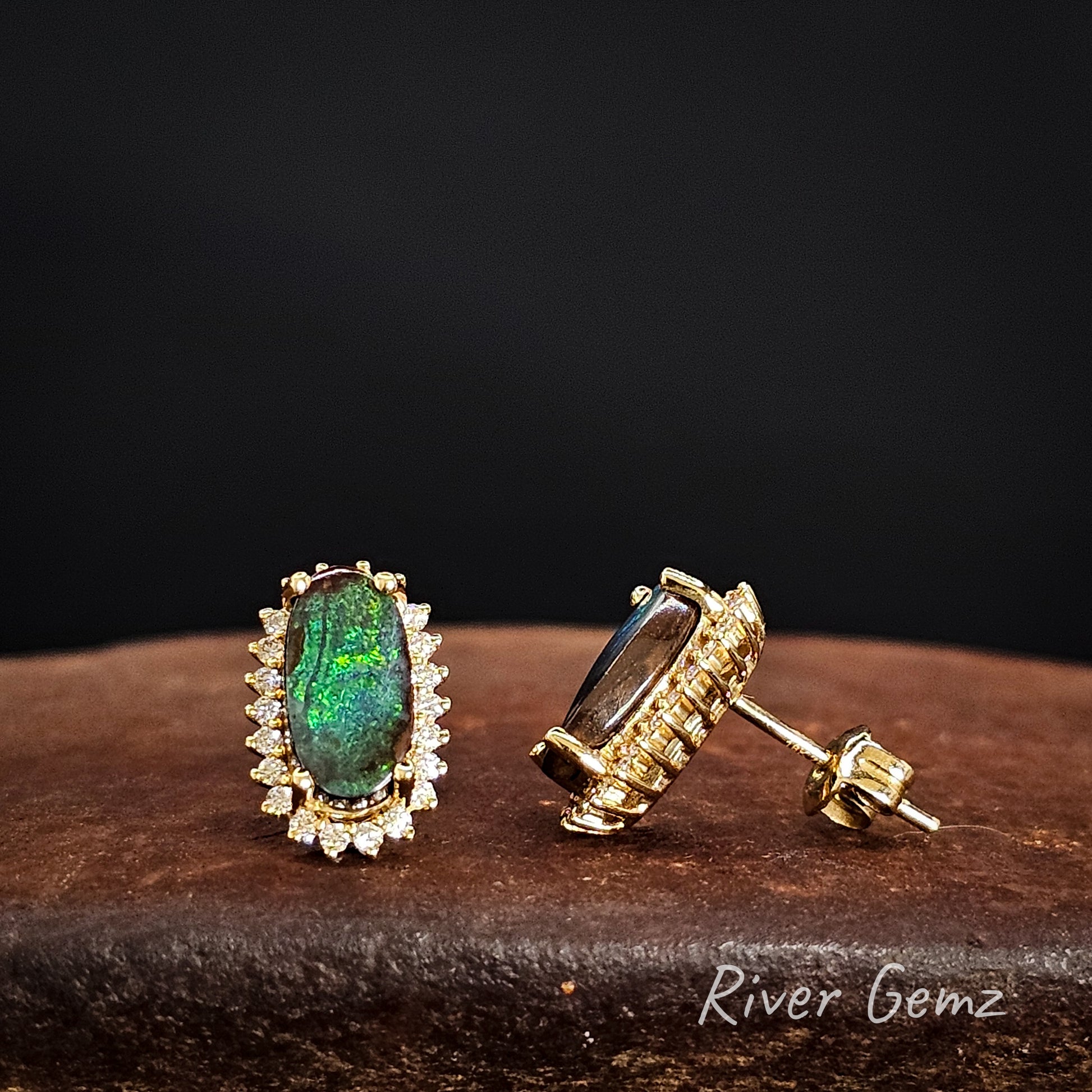 Gold earrings with green boulder opal and multiple white diamonds on a dark background, featuring 'River Gemz' branding.