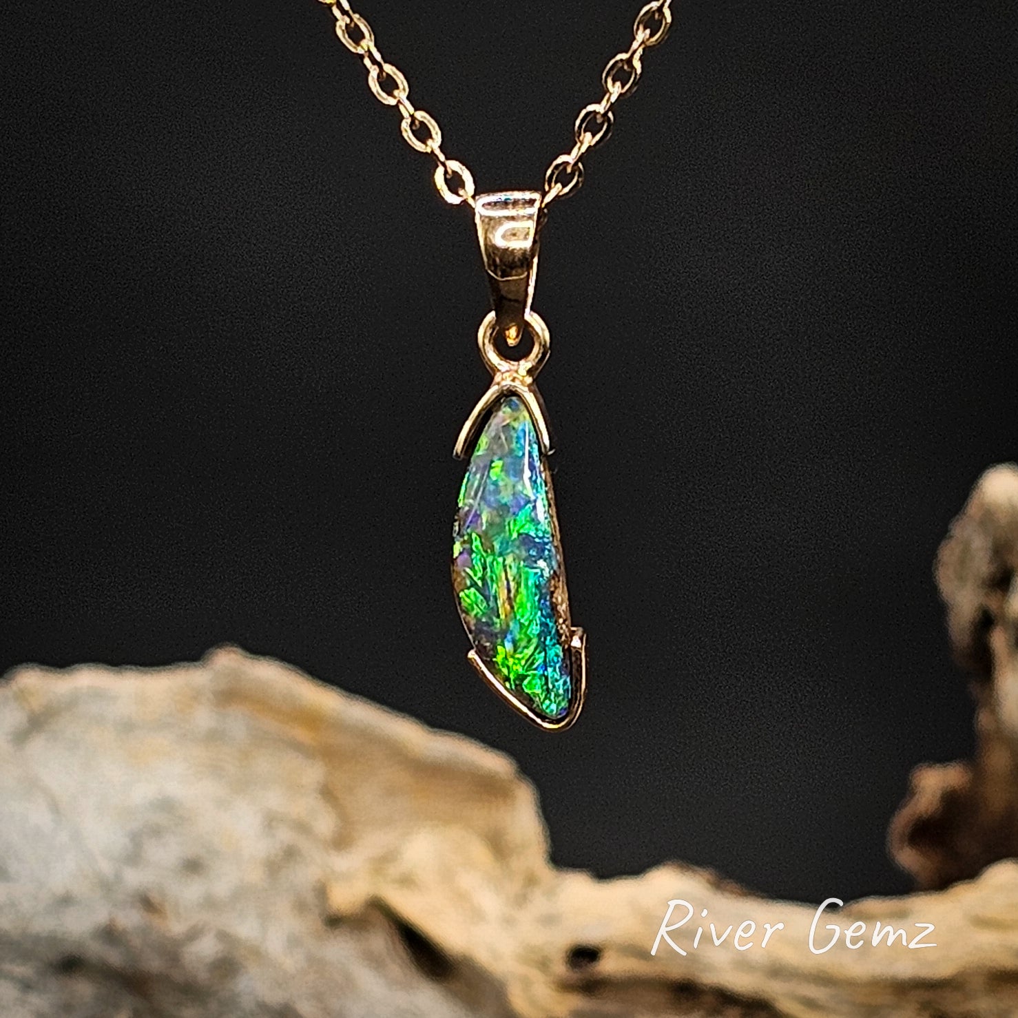 Green and blue boulder opal  necklace on a gold chain with a dark background and 'River Gemz' branding.