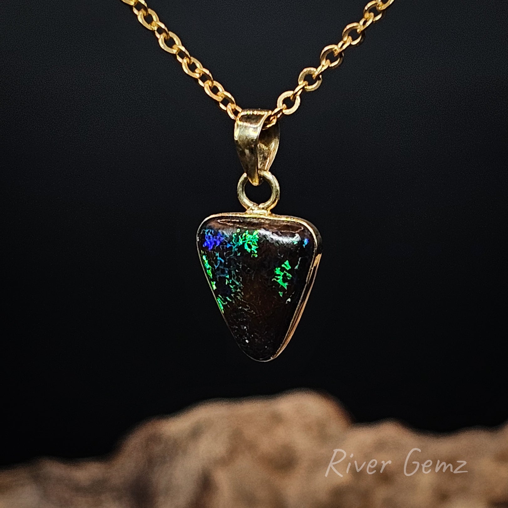 Opal pendant necklace on a gold chain against a dark background with 'River Gemz' branding.
