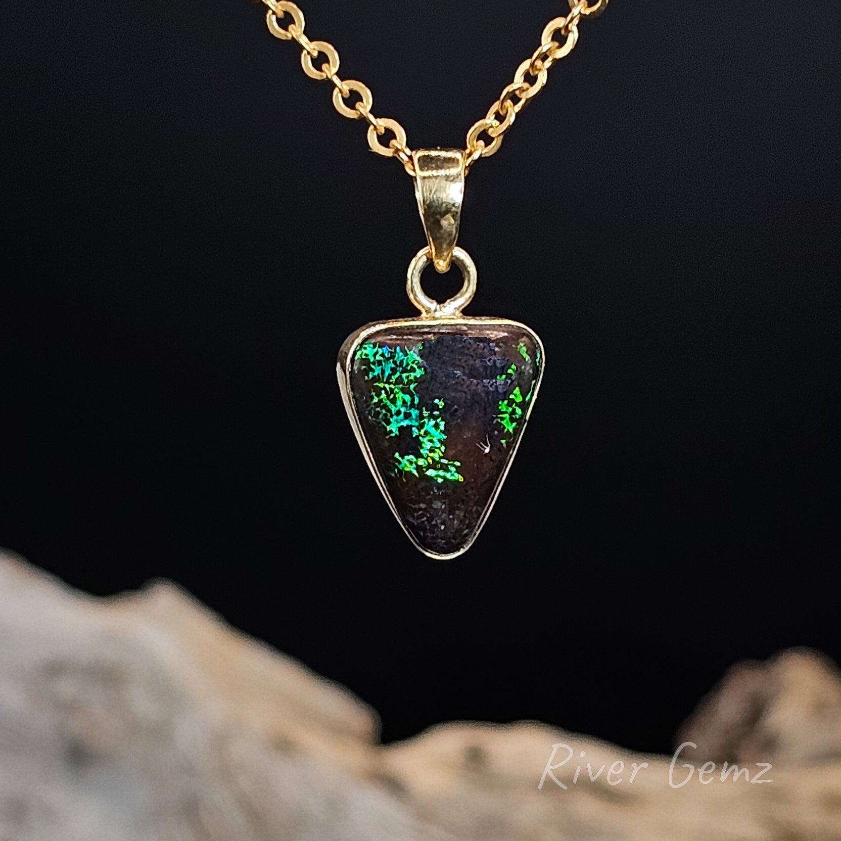 Opal pendant necklace on a gold chain with a dark background