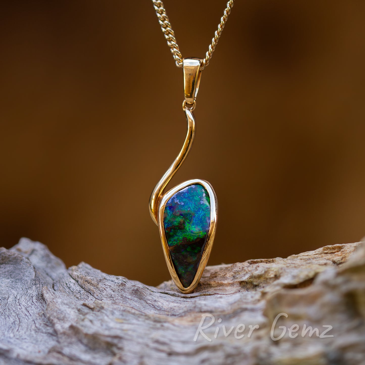 The pendant design resembles a cockle bait, the opal in this case, on the end of a fishing hook. The free-form cut dark green opal contrasts with the high grade gold setting of the necklace.