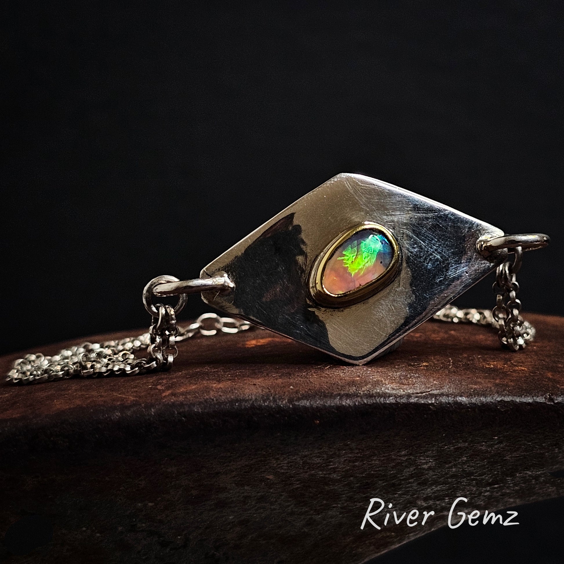 Sterling silver bracelet featuring a colourful crystal opal on a dark background, branded 'River Gemz'.