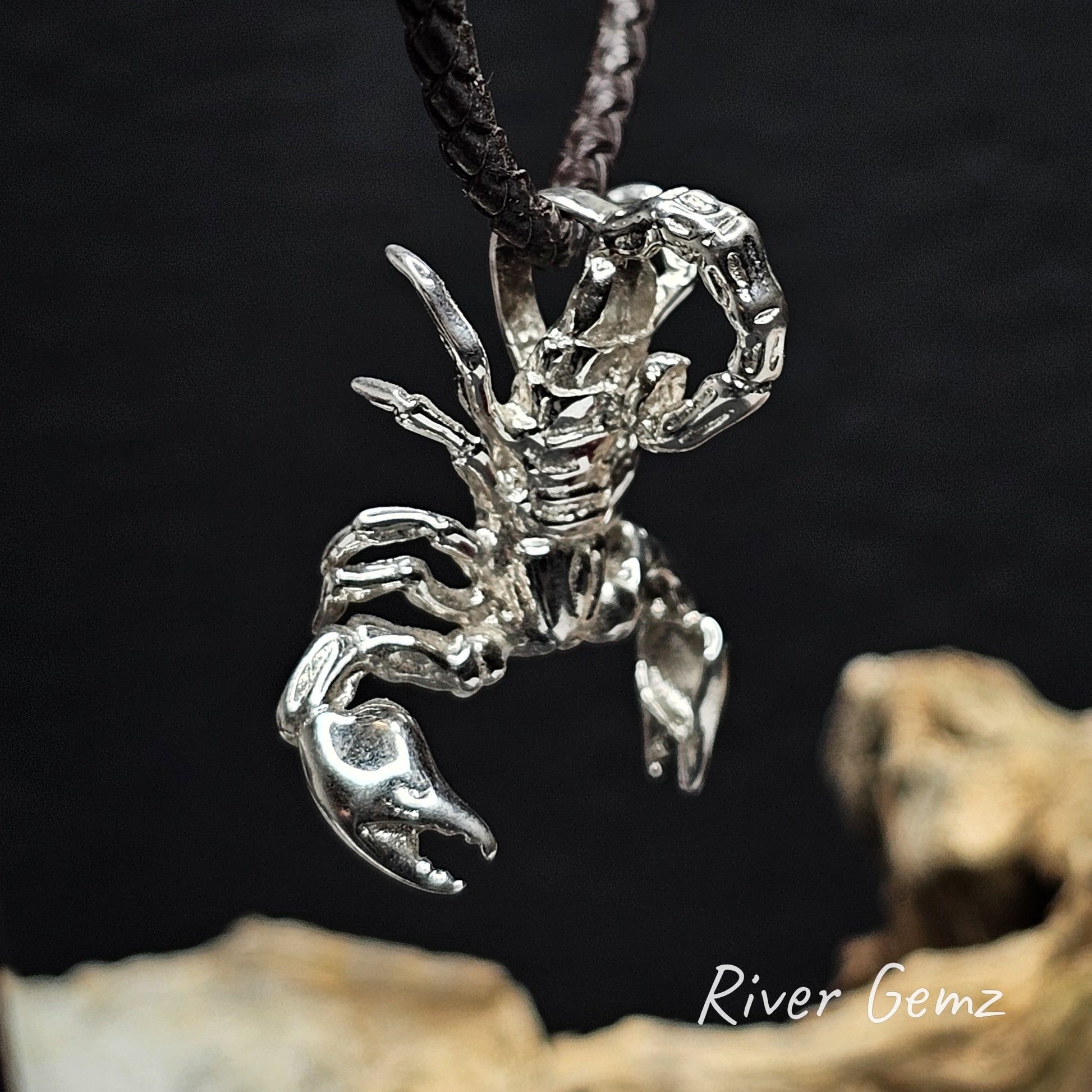 Silver scorpion pendant on a dark background with 'River Gemz' branding.