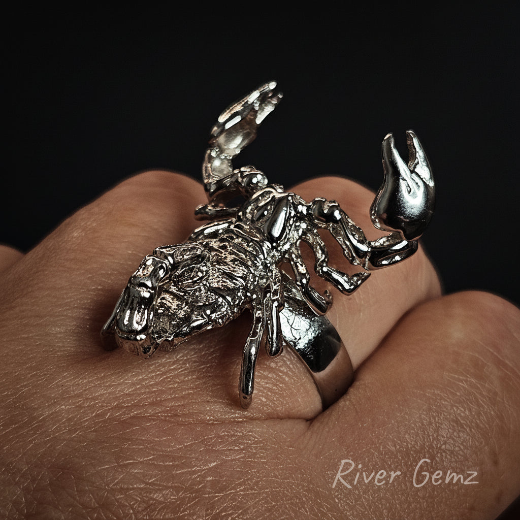Silver scorpion-shaped ring on a finger with 'River Gemz' branding.