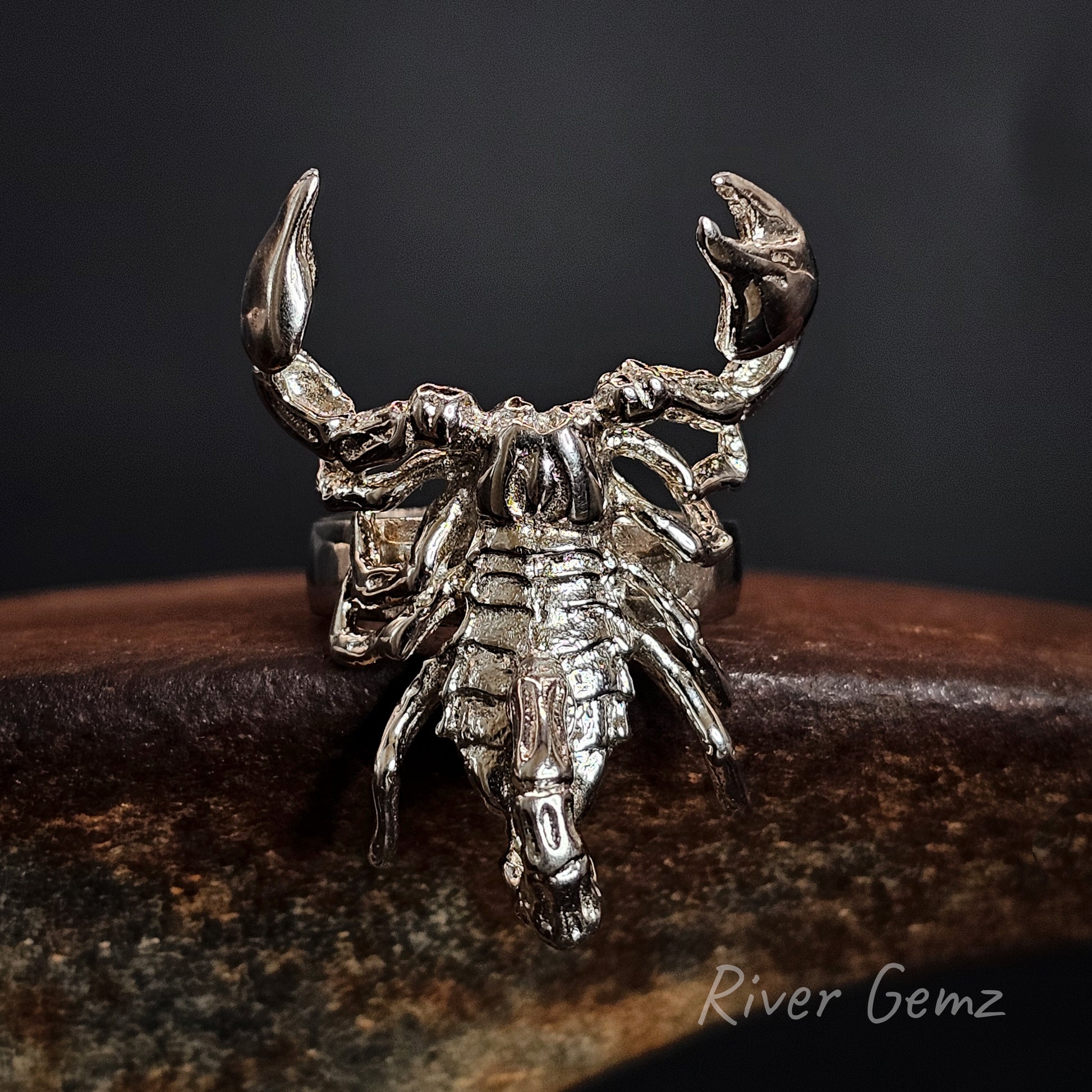 Silver scorpion-shaped ring on a dark background