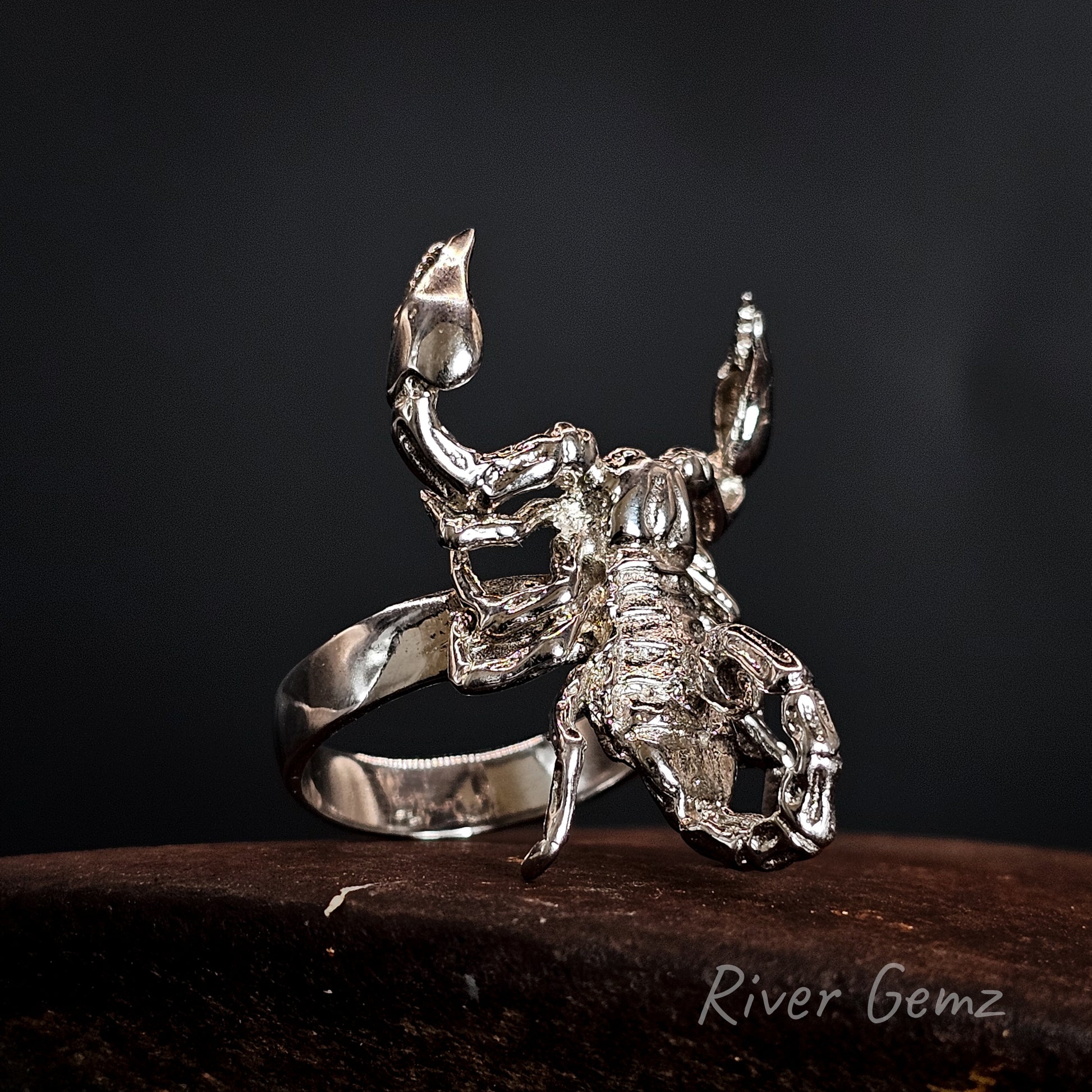 Silver scorpion-shaped ring on a dark background